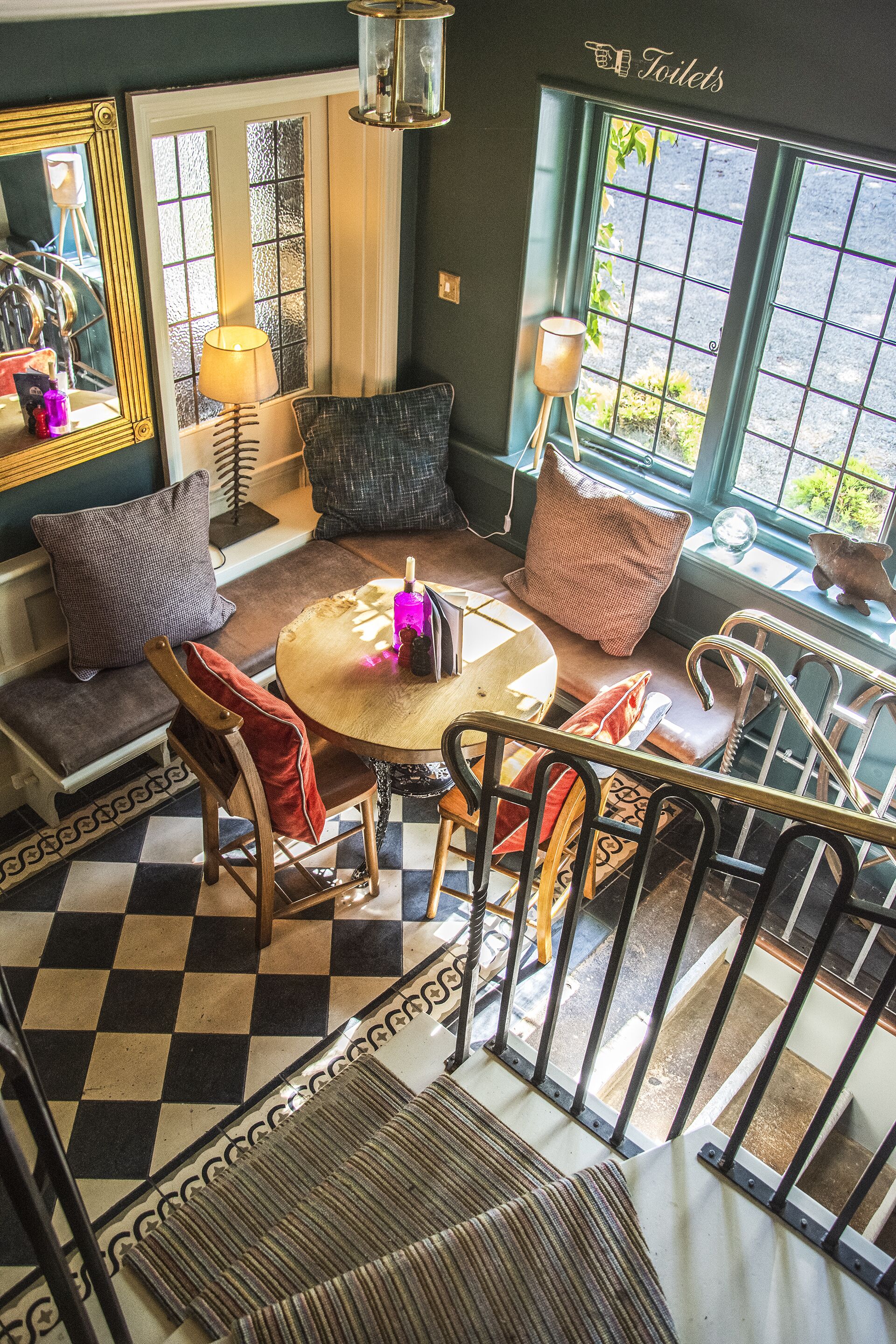 A cozy seating area with a checkered floor, a round table, and a view of the outdoors through a window.