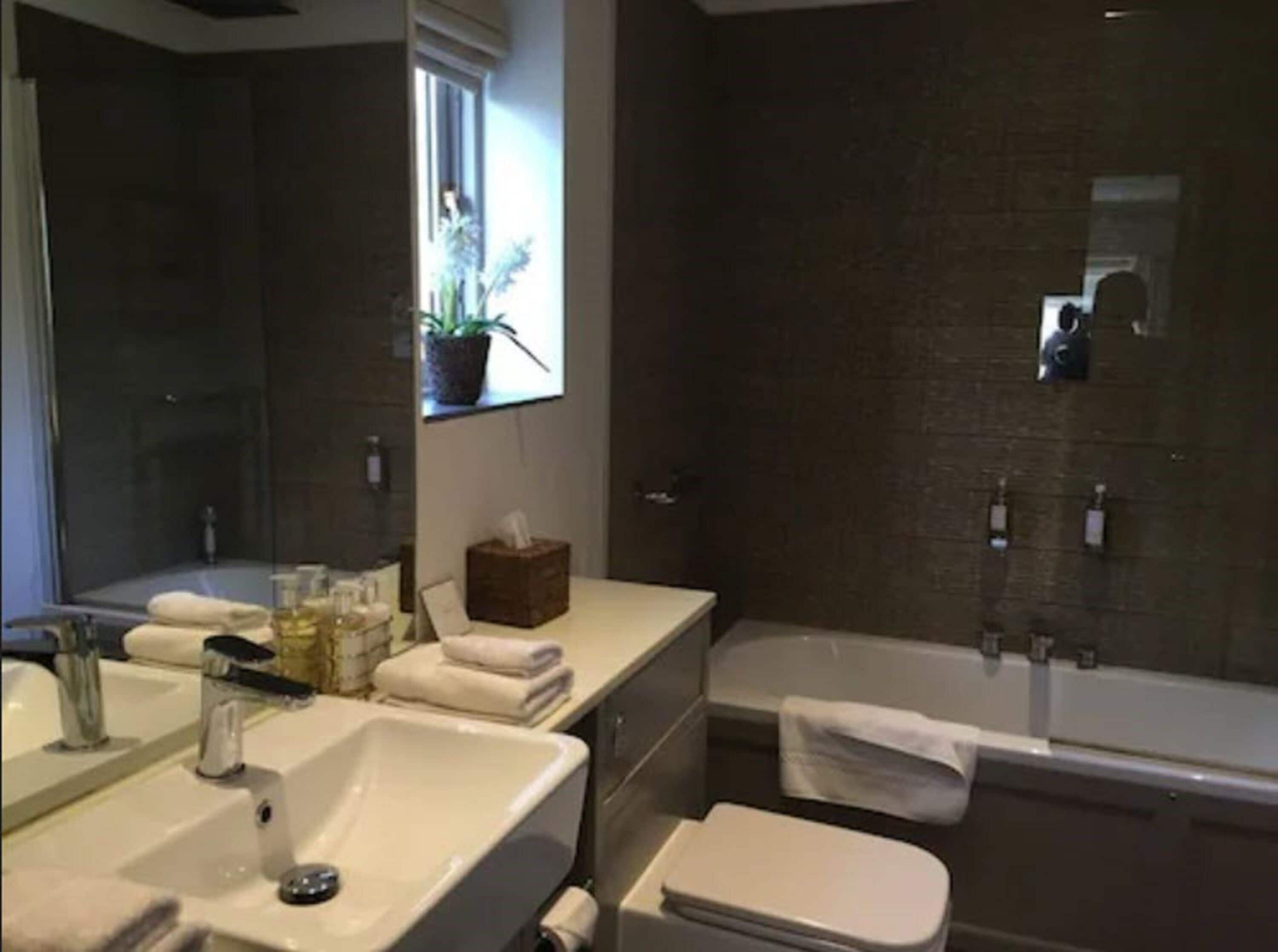 A modern bathroom with a large mirror, a sink, a bathtub, and a shower area.