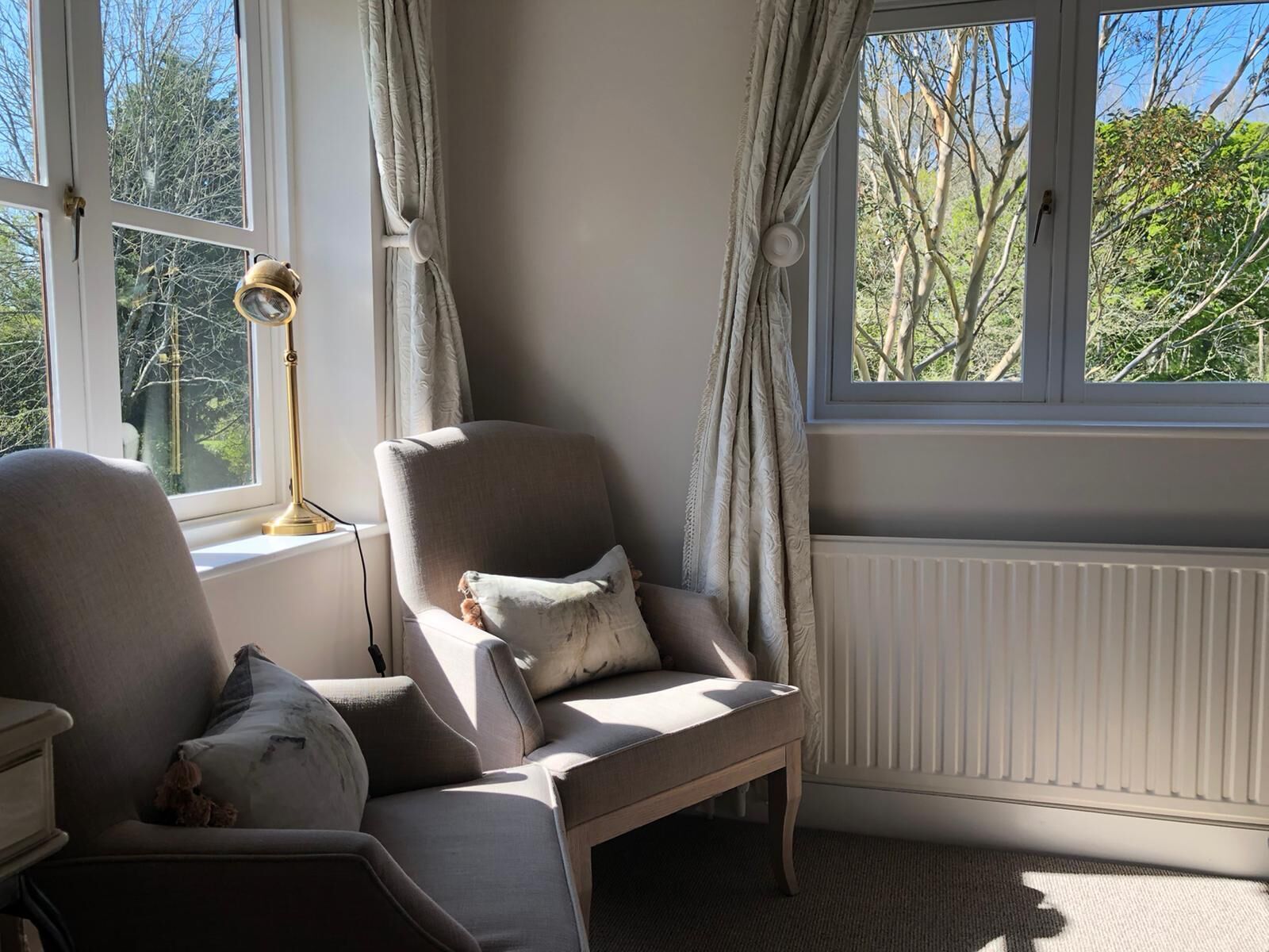 A cozy room with a large window, a radiator, and a lamp.