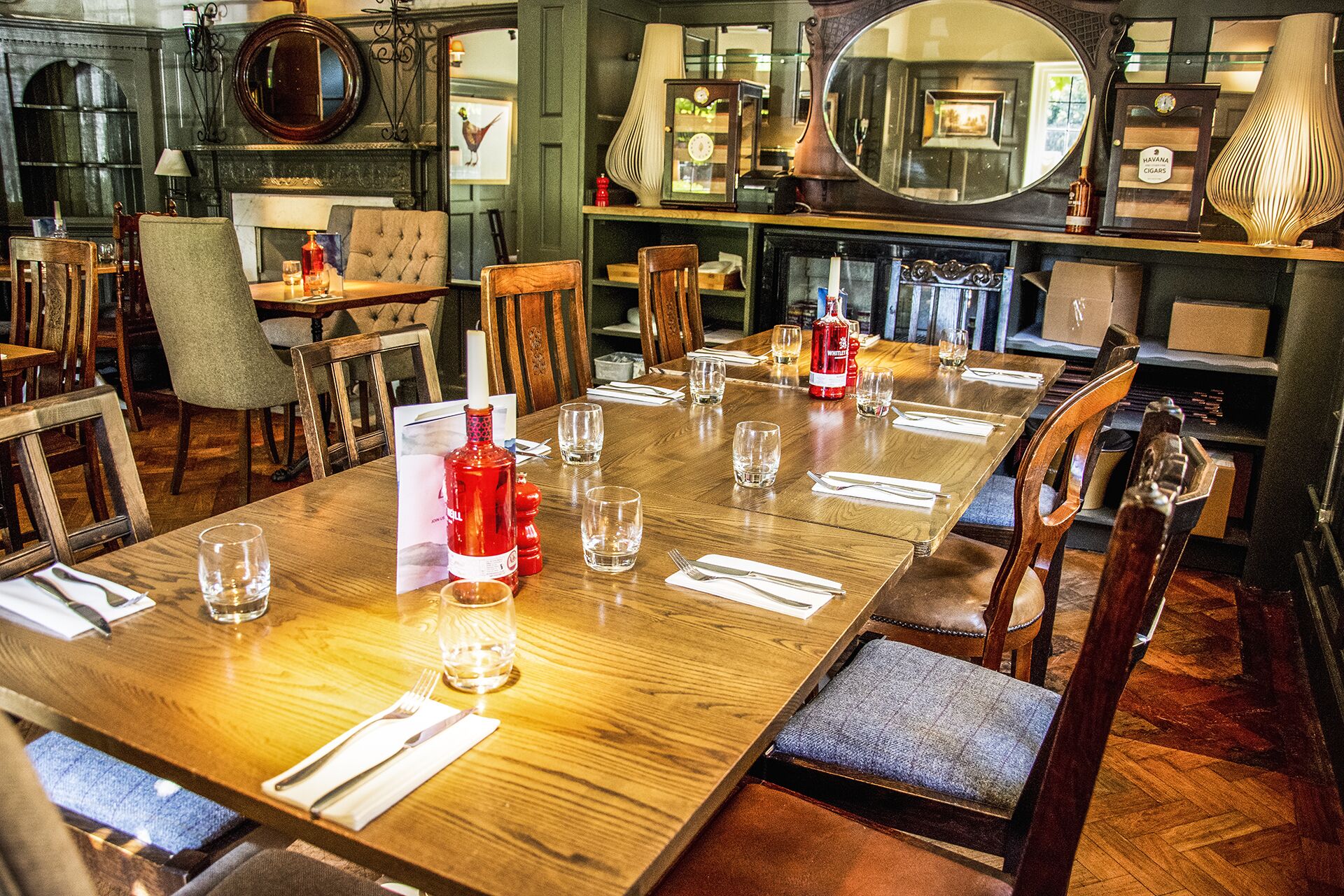A dining area with a long wooden table set for a meal, surrounded by wooden chairs.