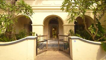 A building entrance with a gate, arched doorways, and surrounding greenery.