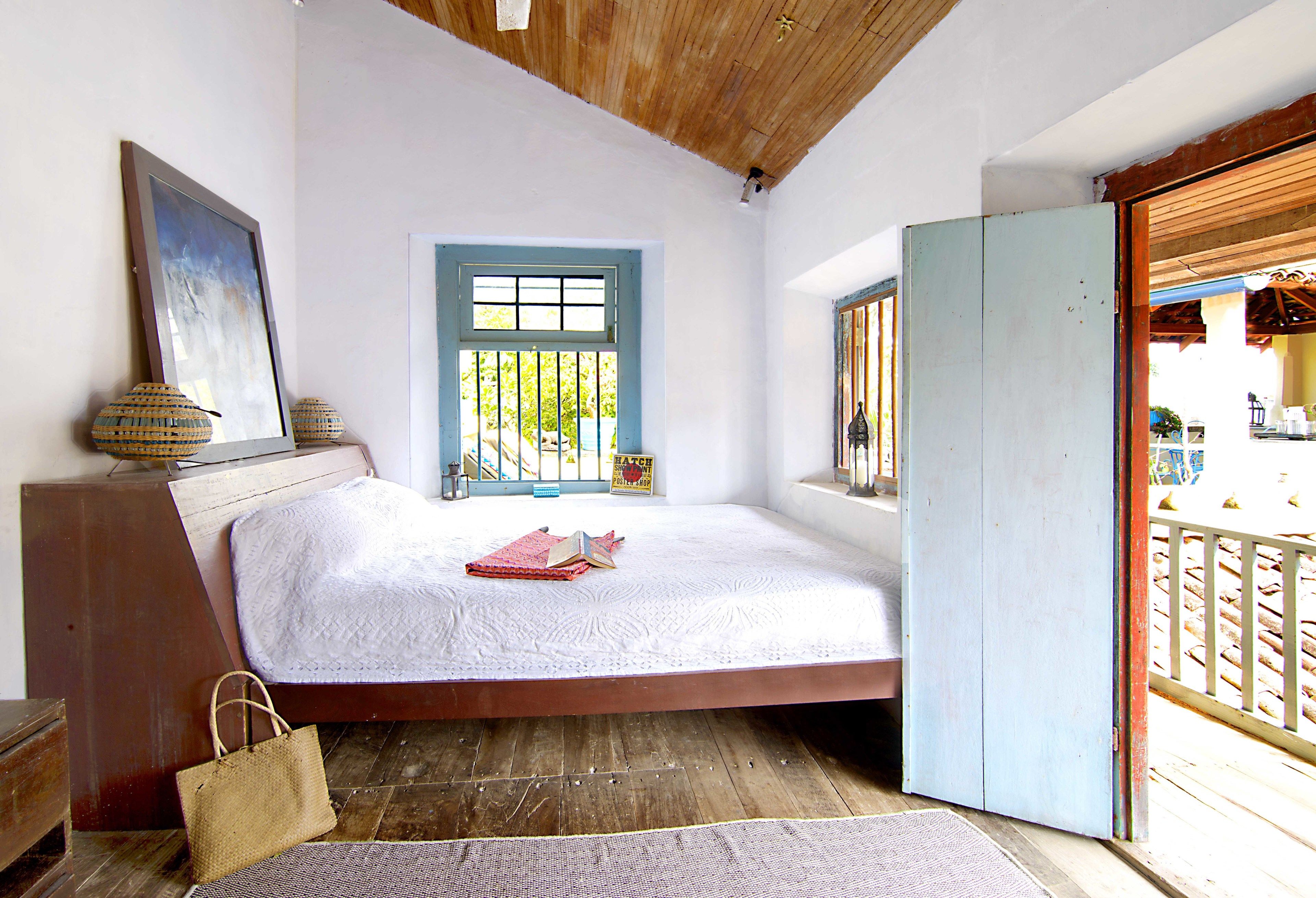 Un dormitorio con cama, ventana, puerta y techo de madera.