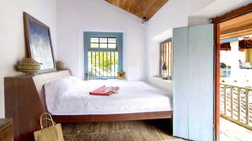 Un dormitorio con cama, ventana, puerta y techo de madera.