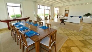 Un comedor amplio con una larga mesa de madera dispuesta para una comida, rodeada de sillas.