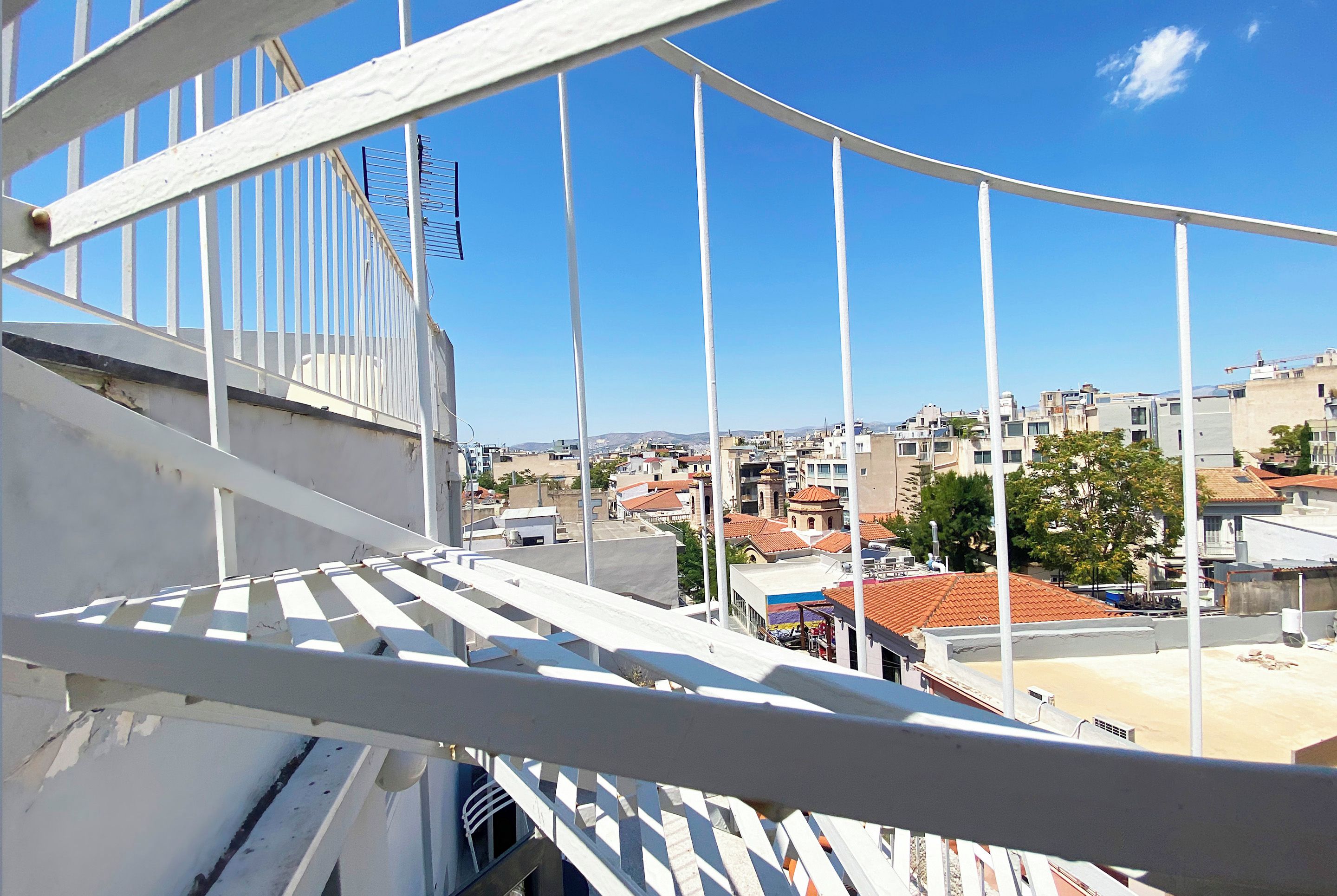 A balcony with a view of a cityscape, including buildings and a clear sky.