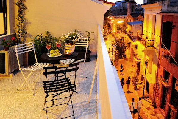 A balcony with a table set for two, chairs, and a potted plant. - Live in Athens, Psyrri Central Apartments (Athens)