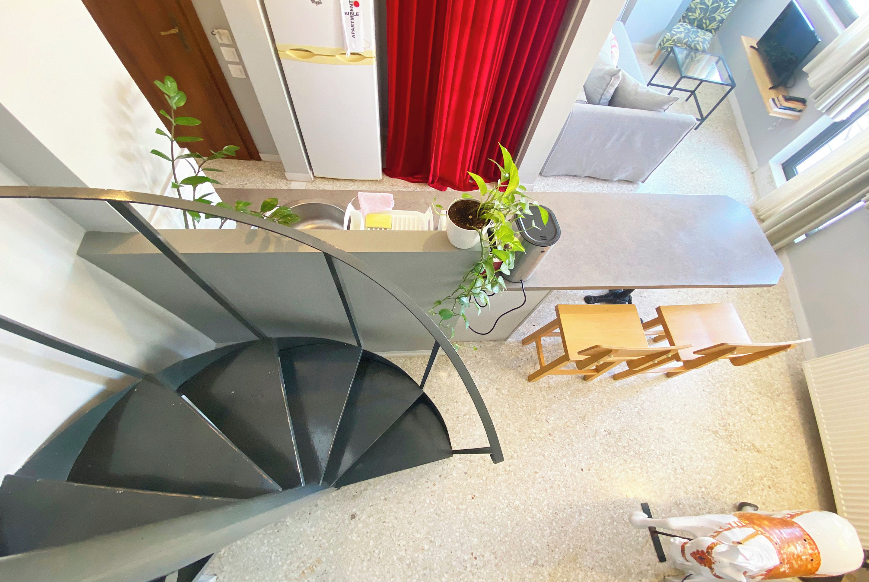 Ein modernes Interieur mit einer Wendeltreppe, einem Essbereich mit Tisch und Stühlen, einer Couch und einem Blumentopf.