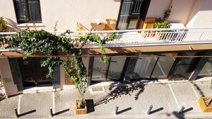 A building with a balcony, outdoor seating, and potted plants. - Live in Athens, Psyrri Central Apartments (Athens)