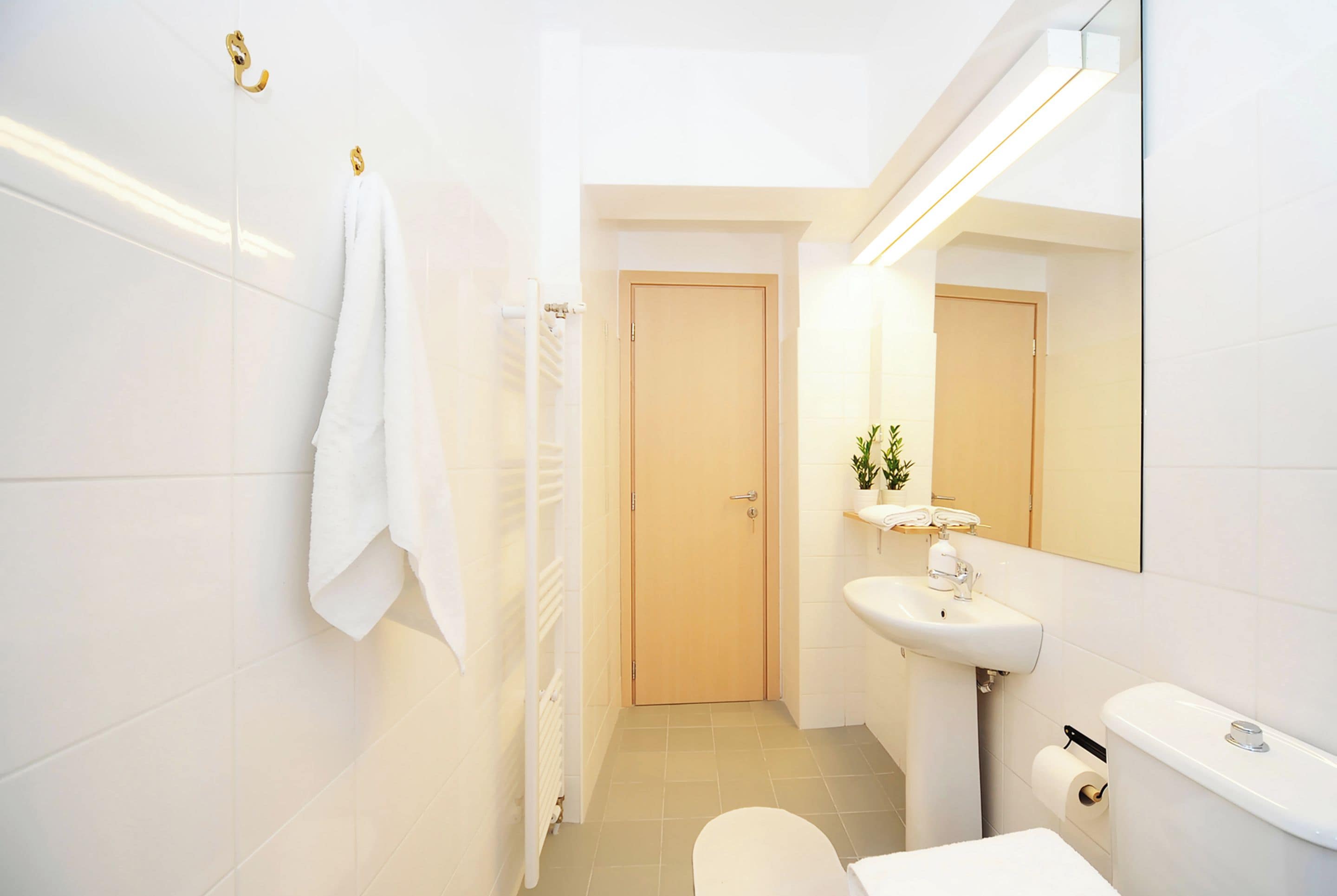 A bathroom with a toilet, sink, and towel rack.