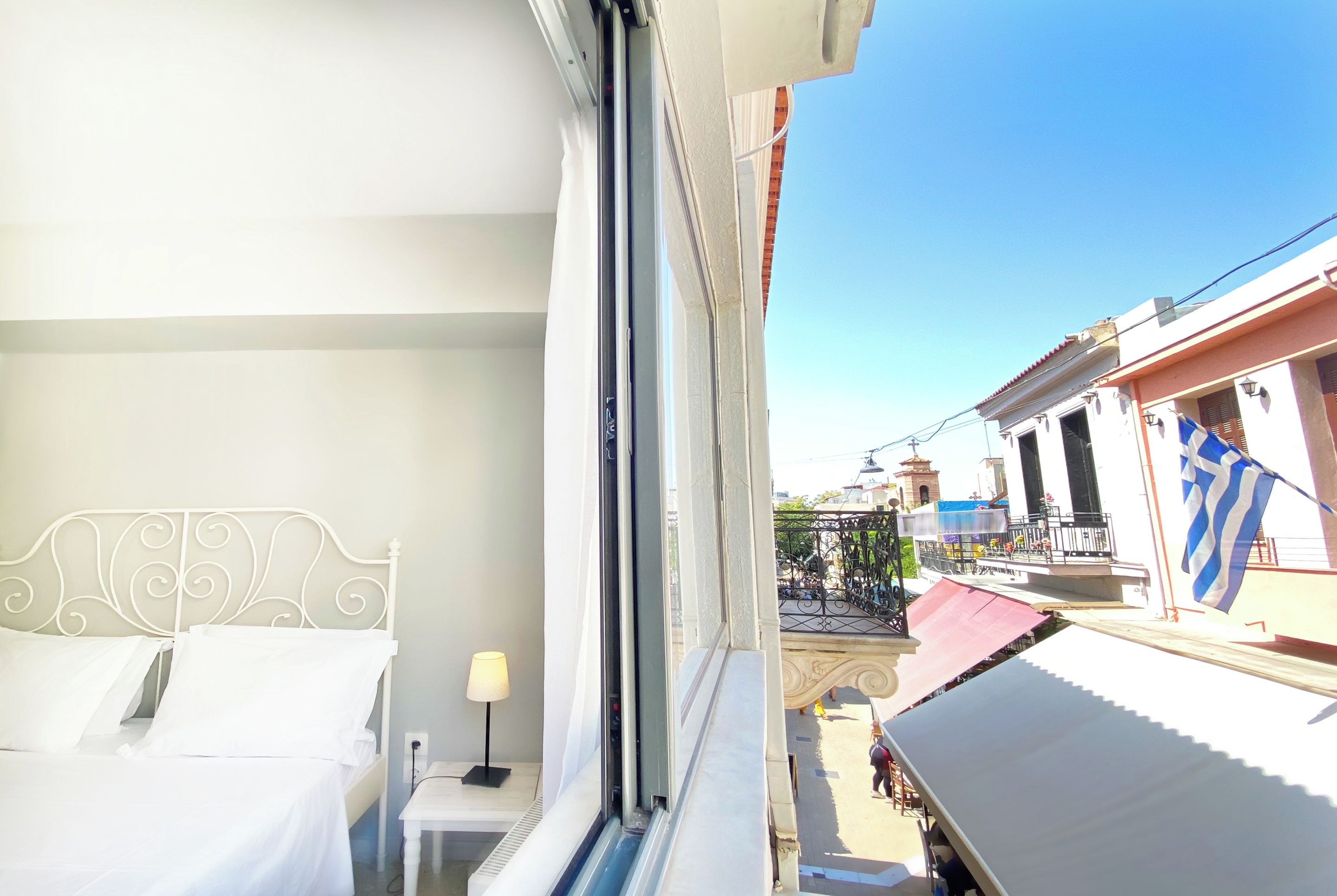 A hotel room with a bed, a bedside table, and a window overlooking a street.