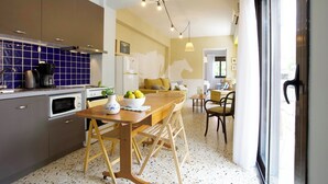 A modern kitchen with a dining area, featuring a wooden table, chairs, and a kitchen island. - Live in Athens, Psyrri Central Apartments (Athens)