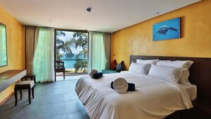 A hotel room with a large bed, a desk, and a view of the ocean.