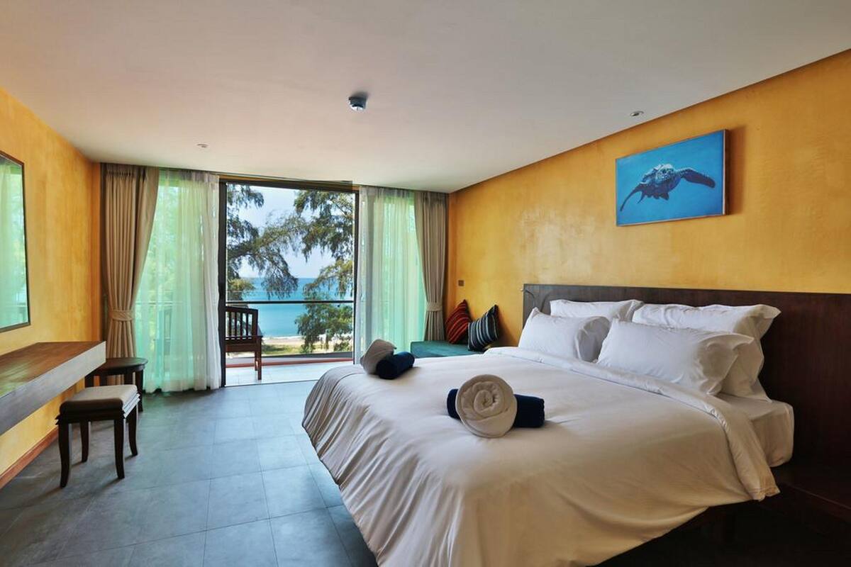Een hotelkamer met een groot bed, een bureau en uitzicht op de oceaan.
