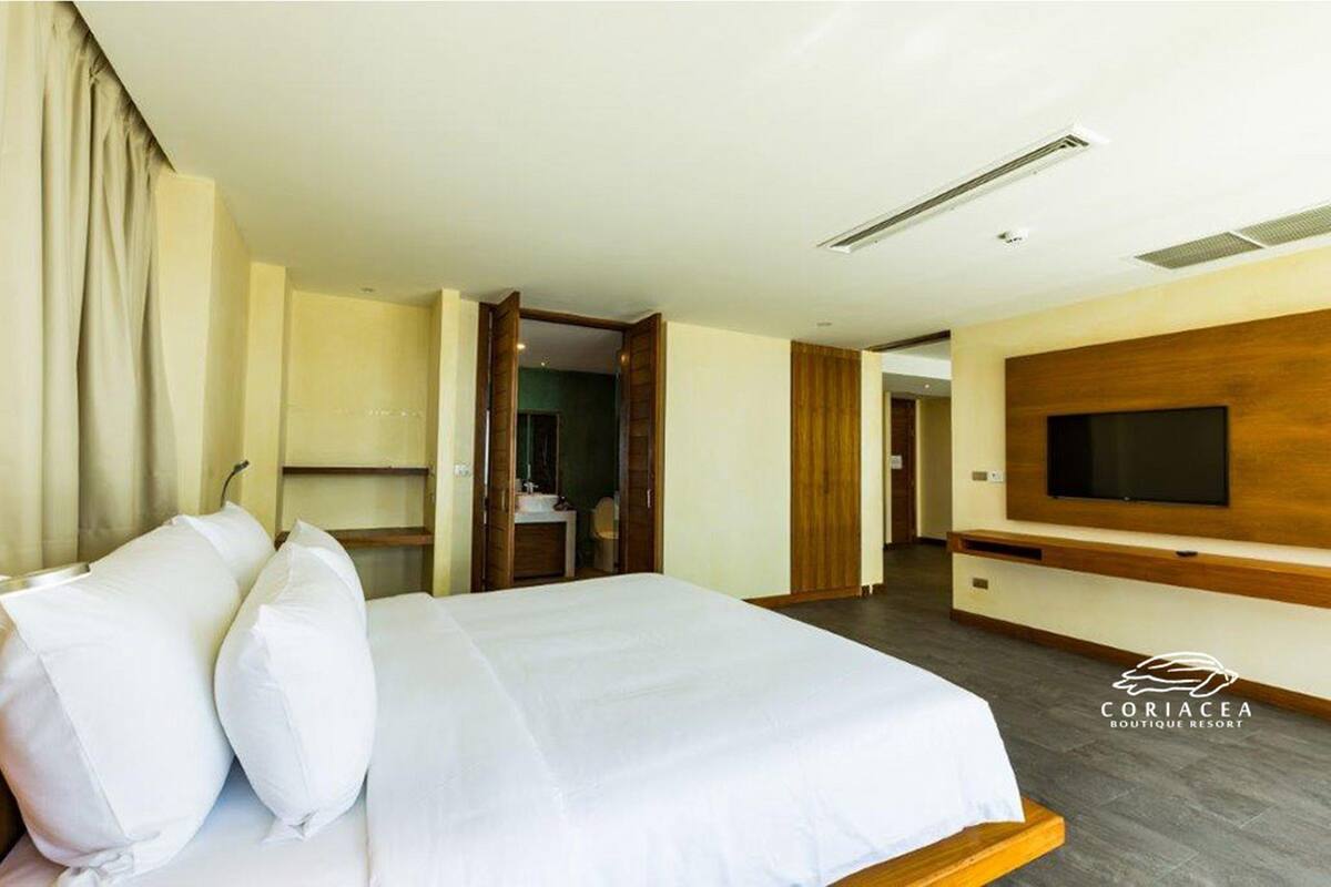 Een hotelkamer met een bed, een aan de muur bevestigde televisie en een deur naar een badkamer.