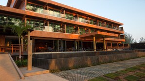 A modern hotel with multiple balconies, outdoor seating, and a pool area.