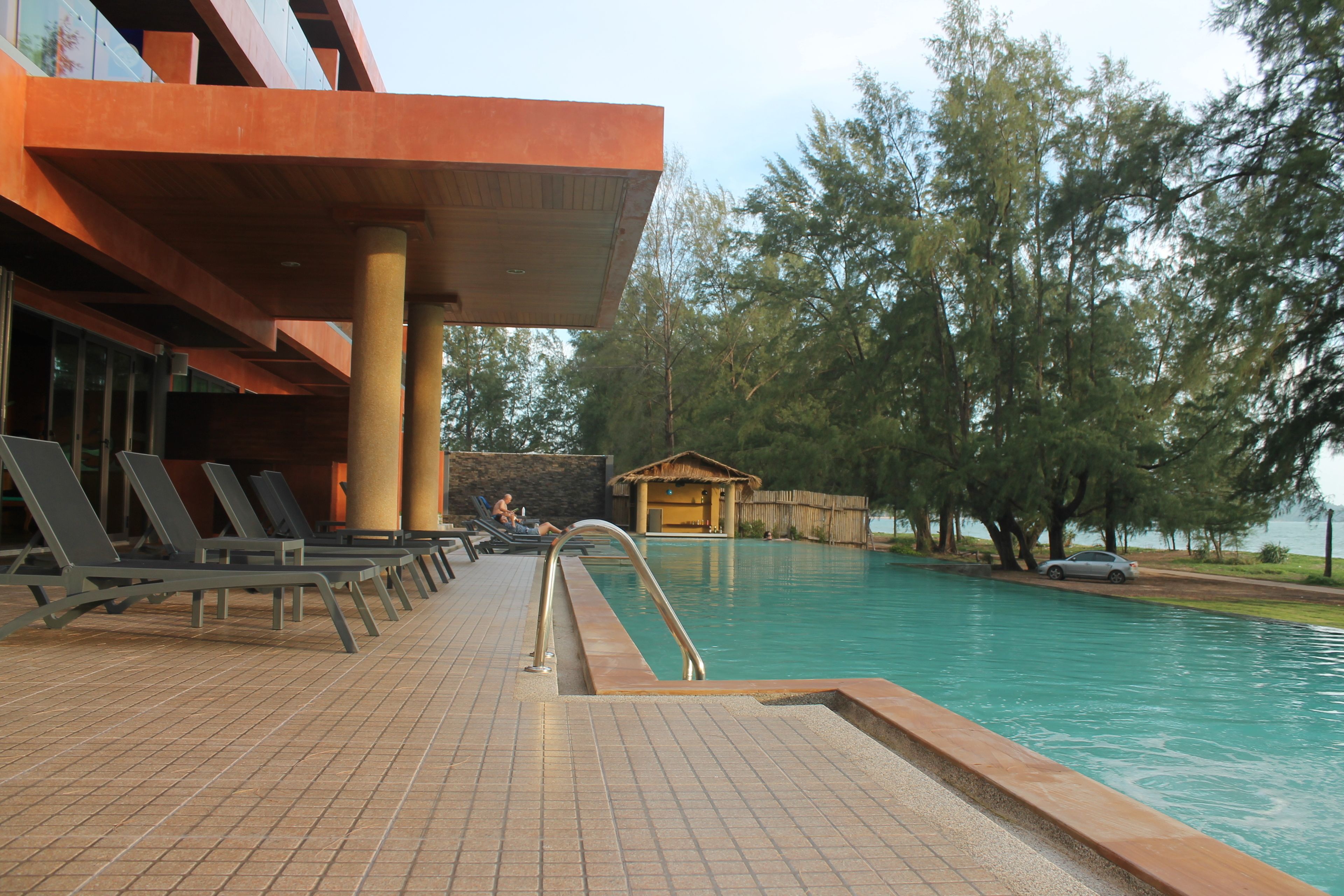 A pool area with lounge chairs, a wooden deck, and a small wooden structure.