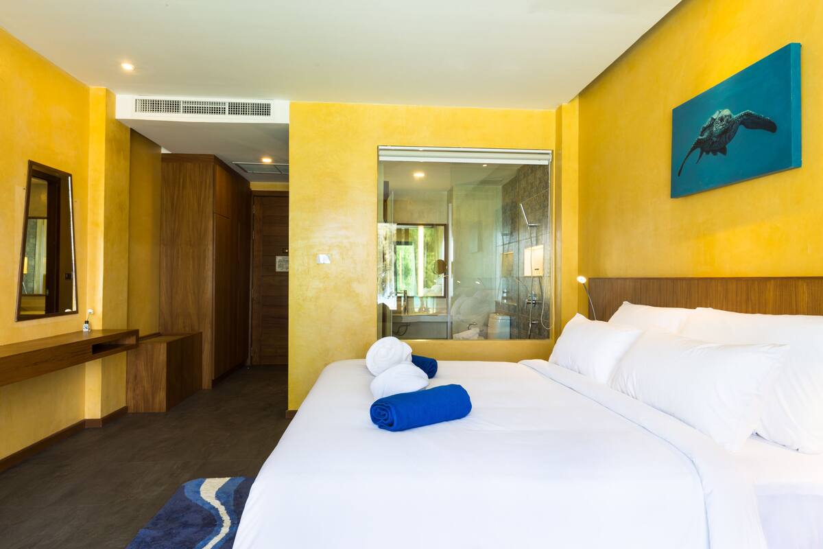 Een hotelkamer met een groot bed, een houten garderobe, een spiegel en een schilderij aan de muur.