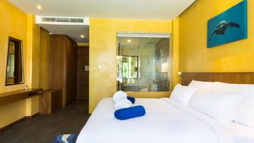 Habitación de hotel con una cama grande, un armario de madera, un espejo y un cuadro en la pared.