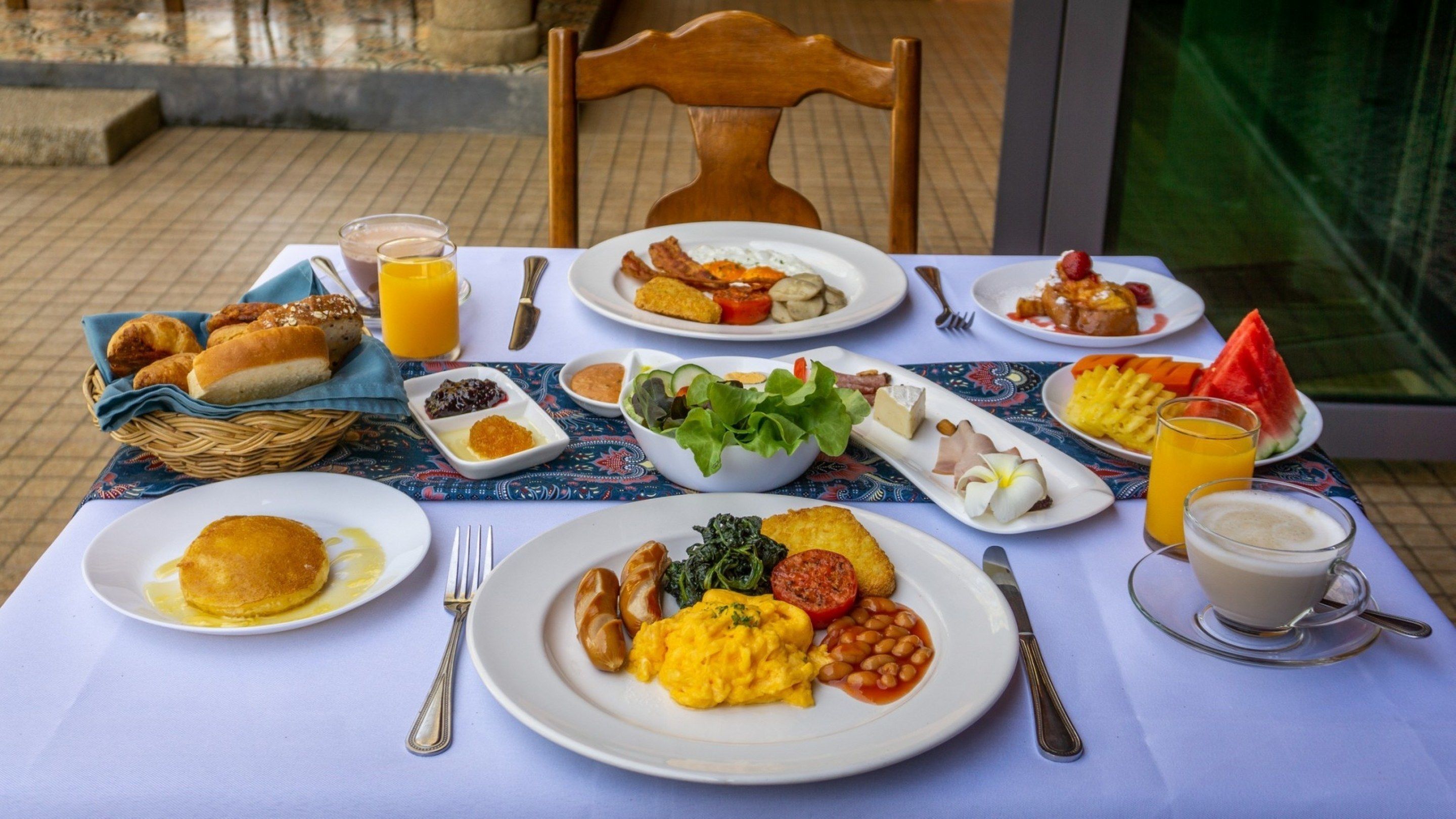 Uma mesa de café da manhã com diversos pratos, incluindo ovos, torradas e frutas.