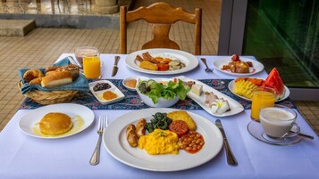 Uma mesa de café da manhã com diversos pratos, incluindo ovos, torradas e frutas.
