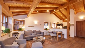 Amplia sala de estar con techo de madera, un sofá, una mesa de centro y un comedor con sillas y una mesa.