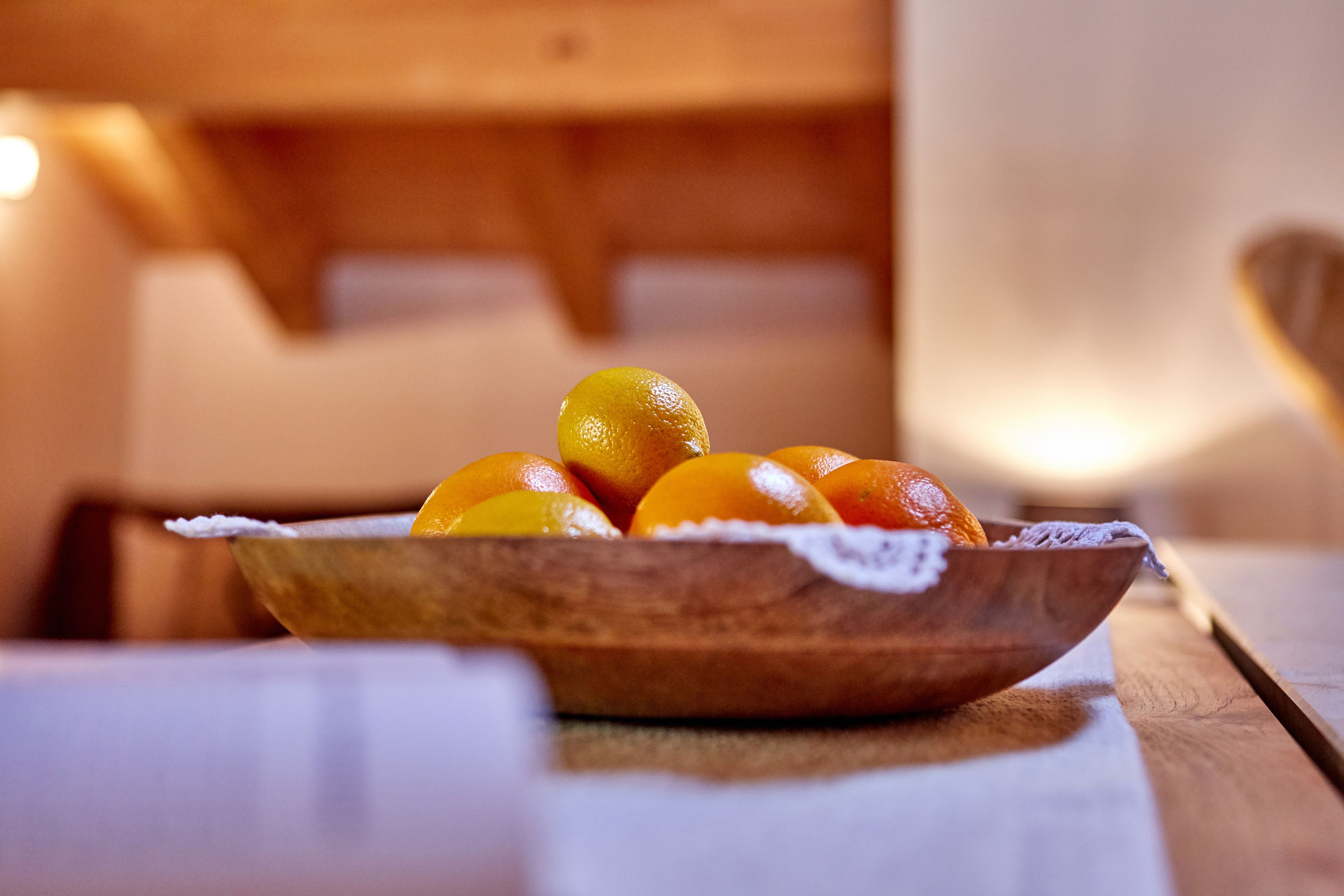 Un saladier en bois contenant des oranges, posé sur une table.