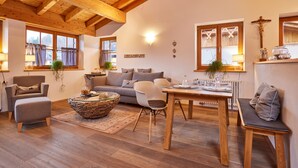 Una sala de estar acogedora con techo de madera, un sofá, una mesa de comedor y un banco.
