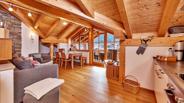 Un interior de madera acogedor con comedor, cocina y vistas amplias a través de ventanas grandes.