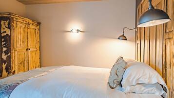 Una camera da letto con un letto grande, un armadio in legno e una lampada a parete.
