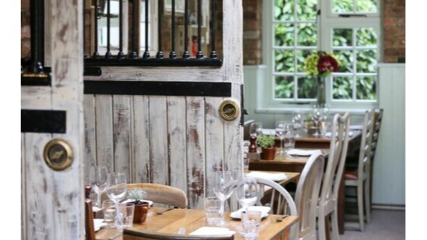 Ein Restaurantinneres mit Holzwänden, einer Bar und gedeckten Tischen.
