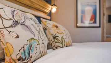 Una cama con almohadas estampadas con motivos florales y un cuadro en la pared.