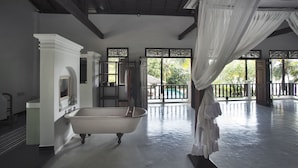 Una habitación amplia con una bañera grande, un armario y un balcón con vistas al exterior.