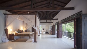 Una habitación amplia con cama, mesita de noche y vistas al exterior.
