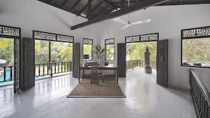 Una habitación amplia con una mesa de madera, sillas y un jarrón decorativo.
