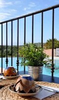 Una mesa con una planta en maceta y un adorno, con vista a una piscina.