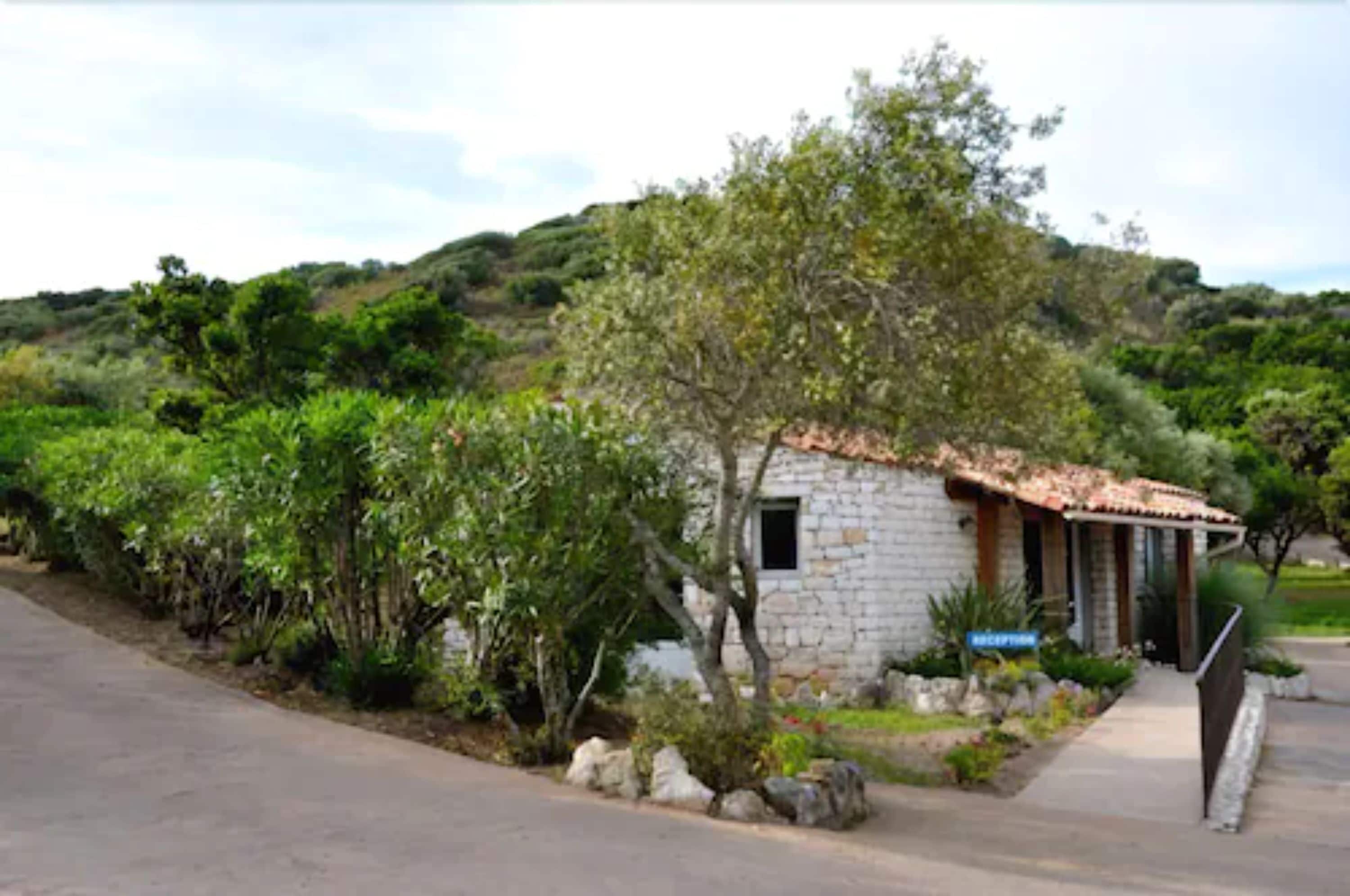 A stone building with a tiled roof, a sign reading "RECEPTION," and a paved path leading to it.