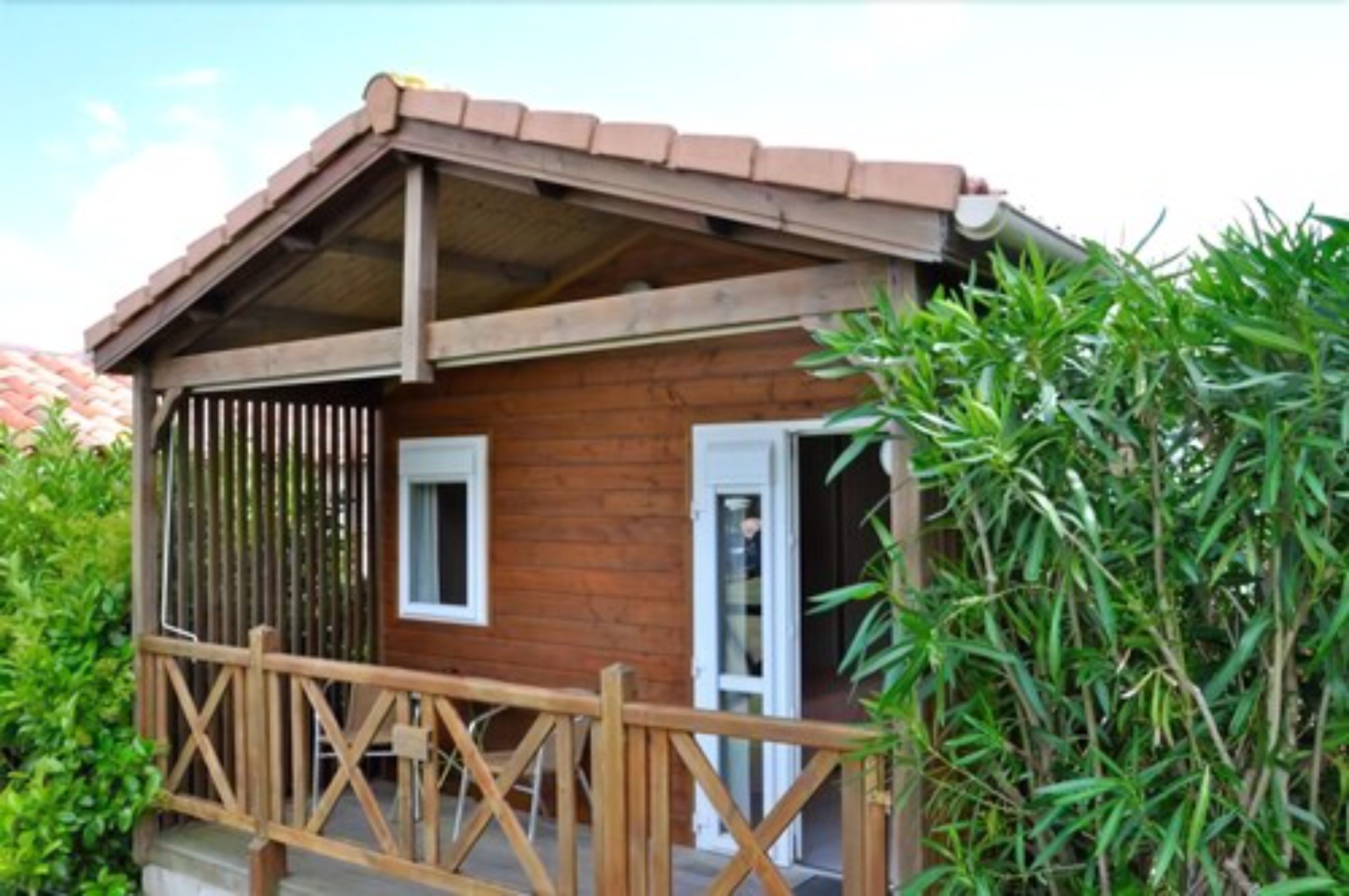 Une cabane en bois dotée d’un balcon, d’une porte et d’une fenêtre.