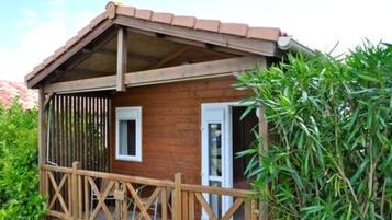 A wooden cabin with a balcony, a door, and a window.