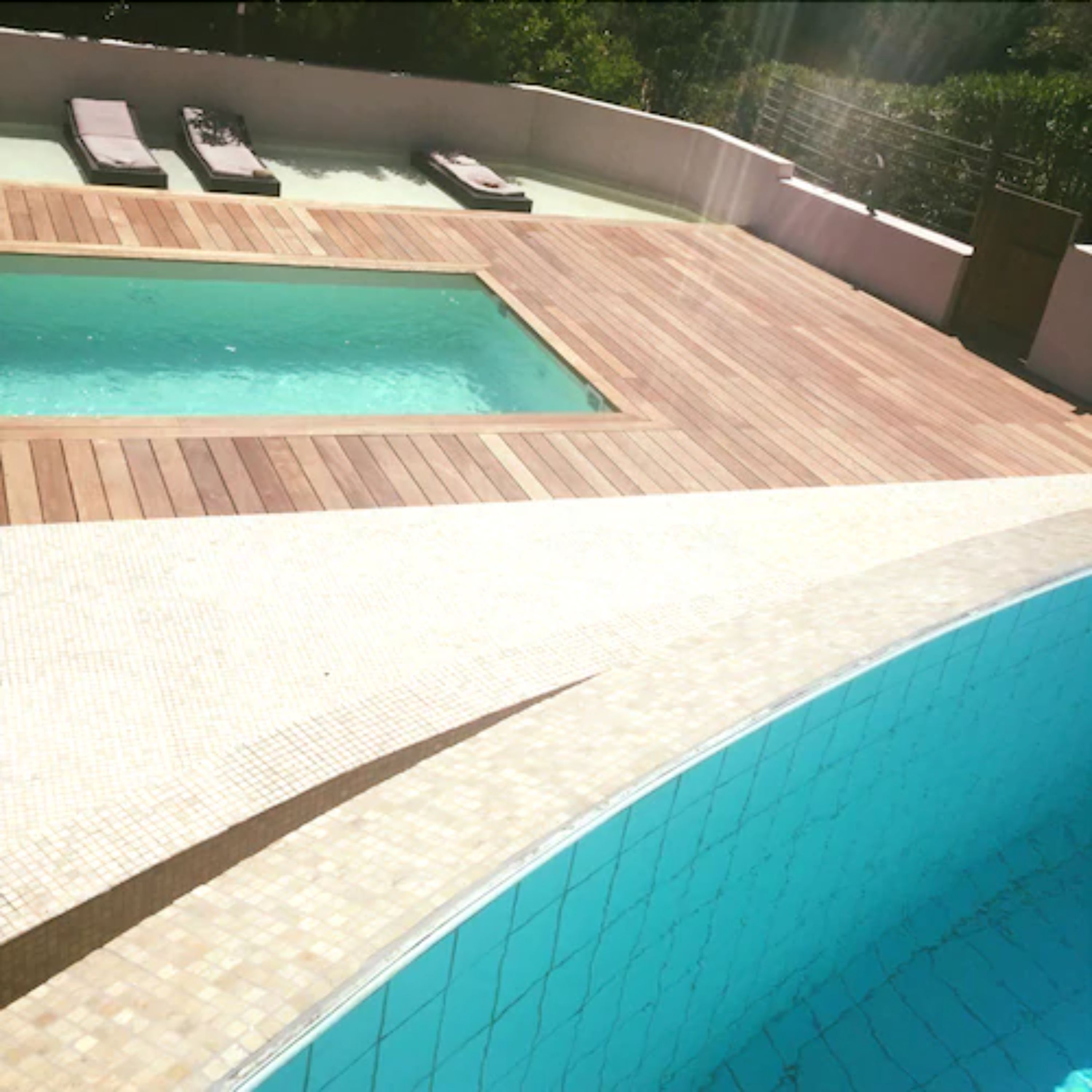 Una piscina con muelle de madera y sillas de descanso.