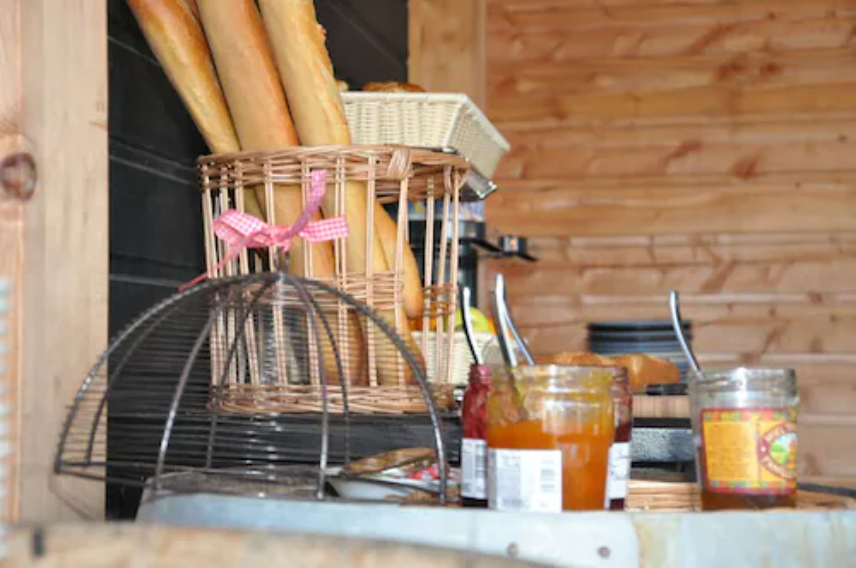 Een mand met stokbroden, een rieten mand en potten honing op een houten ondergrond.
