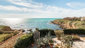 Un paysage côtier avec un mur de pierres, des plantes en pot et une vue sur la mer.