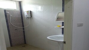A small bathroom with a shower, a sink, and a tiled wall. - GM Modern Place (Udon Thani)