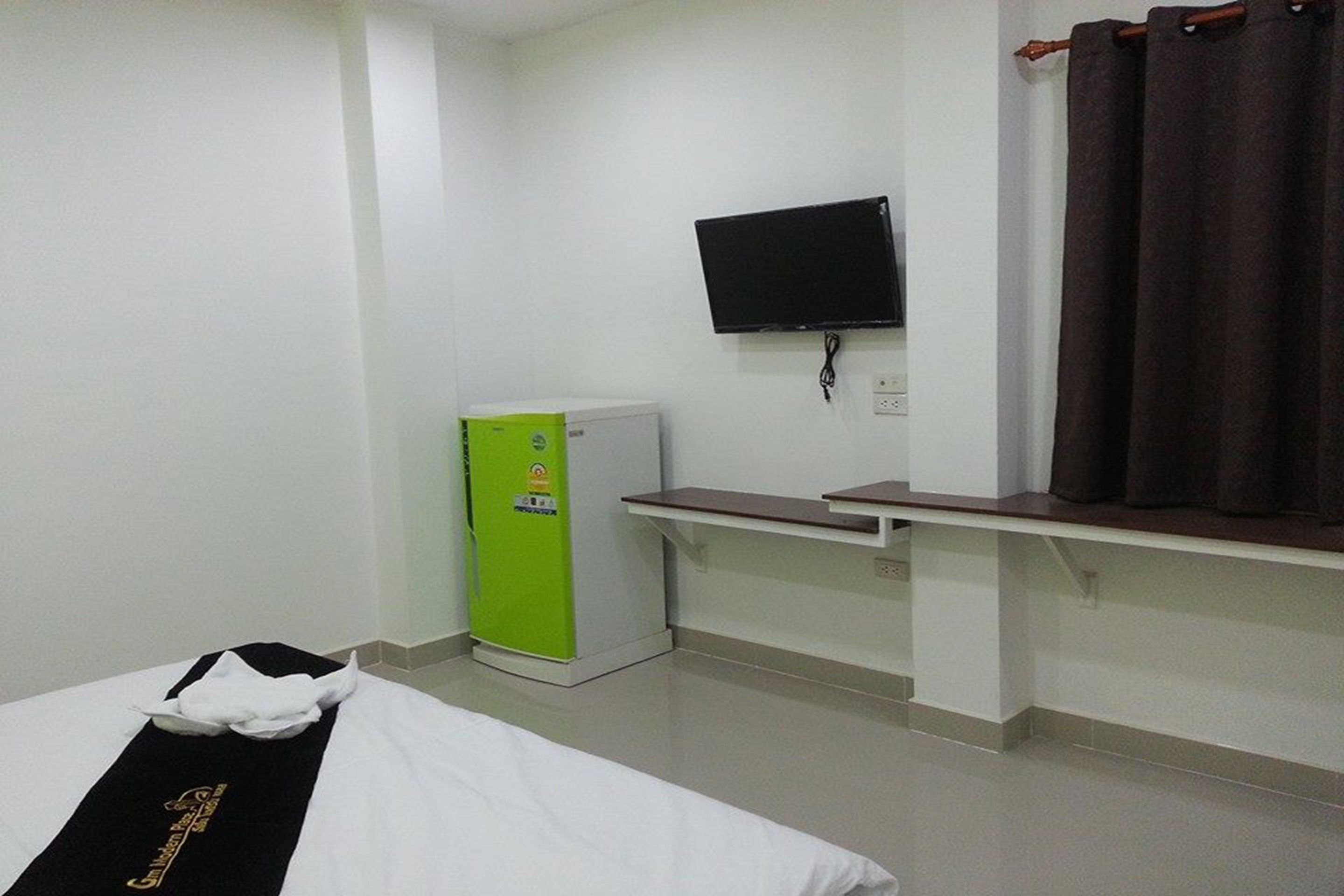 A hotel room with a bed, a desk, a television, and a minibar.