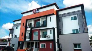 A multi-story building with a prominent 'Gm' sign, balconies, and a car parked in front. - GM Modern Place (Udon Thani)