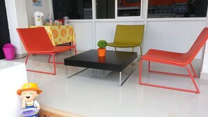 A room with a black table, two red chairs, a yellow tablecloth, a green chair, and a small potted plant. - GM Modern Place (Udon Thani)