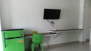 A kitchenette with a green refrigerator, a small table, a chair, and a mounted television. - GM Modern Place (Udon Thani)