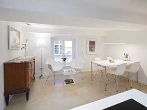 A modern dining area with a white table, chairs, and a wooden cabinet.