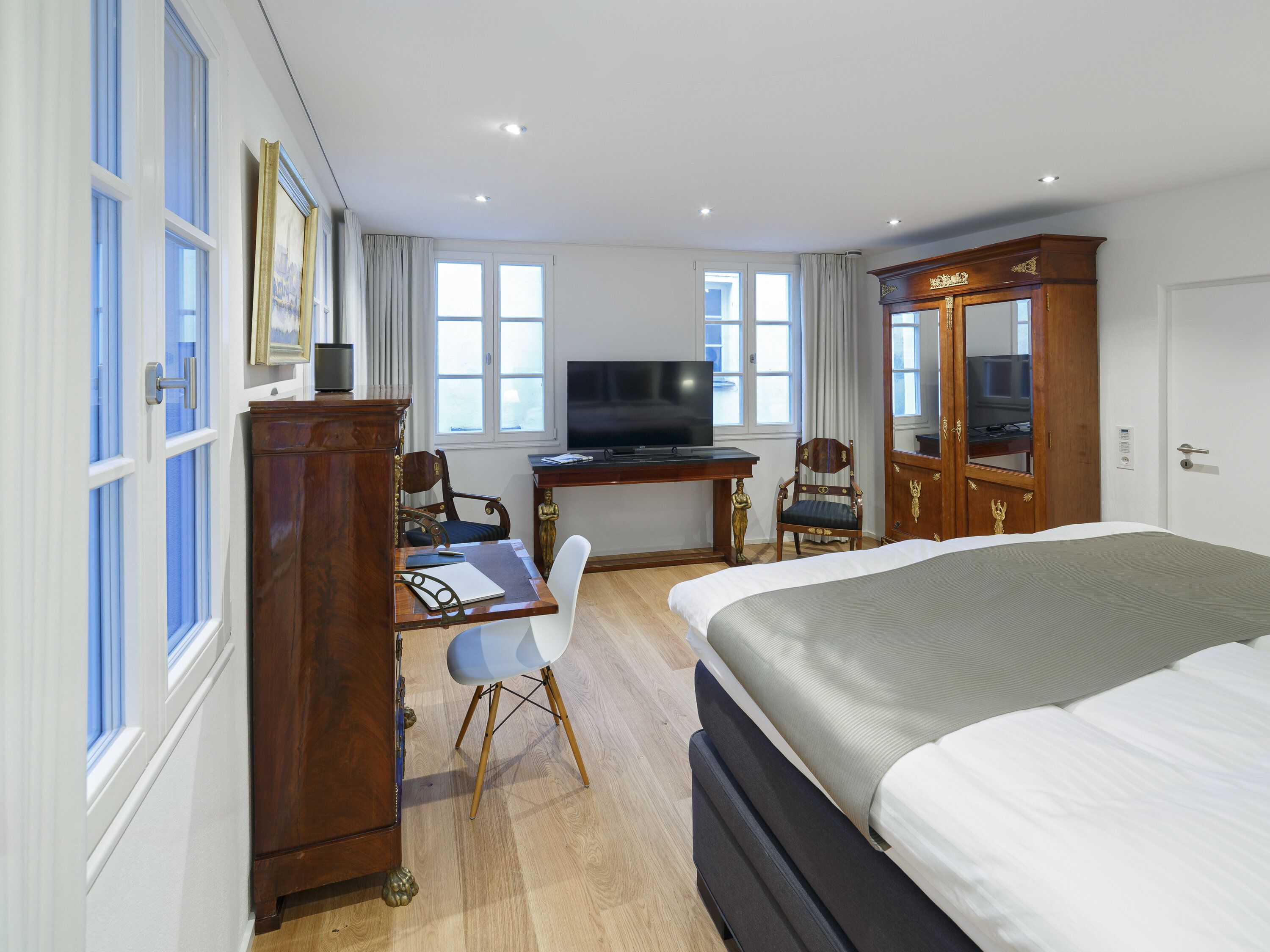 Ein Hotelzimmer mit Bett, Schreibtisch, Fernseher und zwei Stühlen.