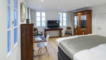 A hotel room with a bed, desk, television, and two chairs.