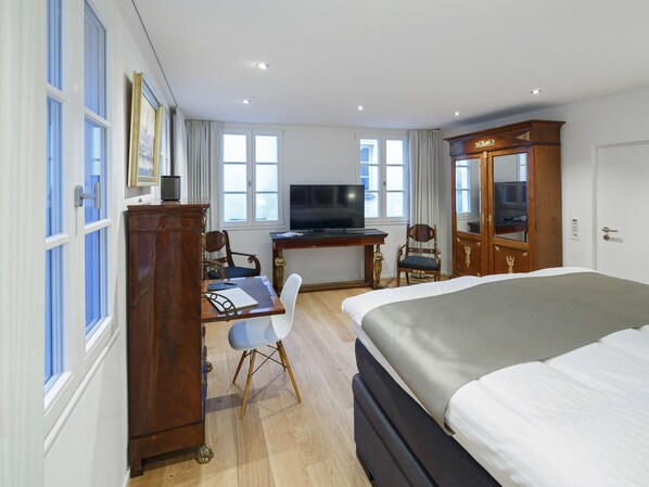 Una habitación de hotel con cama, escritorio, televisión y dos sillas.